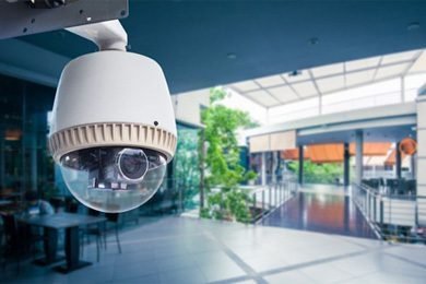 White dome security camera mounted inside a modern shopping mall, representing Singapore video surveillance and remote CCTV monitoring.