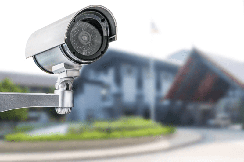 A close-up of a metallic, outdoor bullet-style security camera monitoring a building's exterior, serving as a visual representation of the hardware factors that influence CCTV System Costs in Singapore when building a reliable surveillance system with premium cctv camera systems.